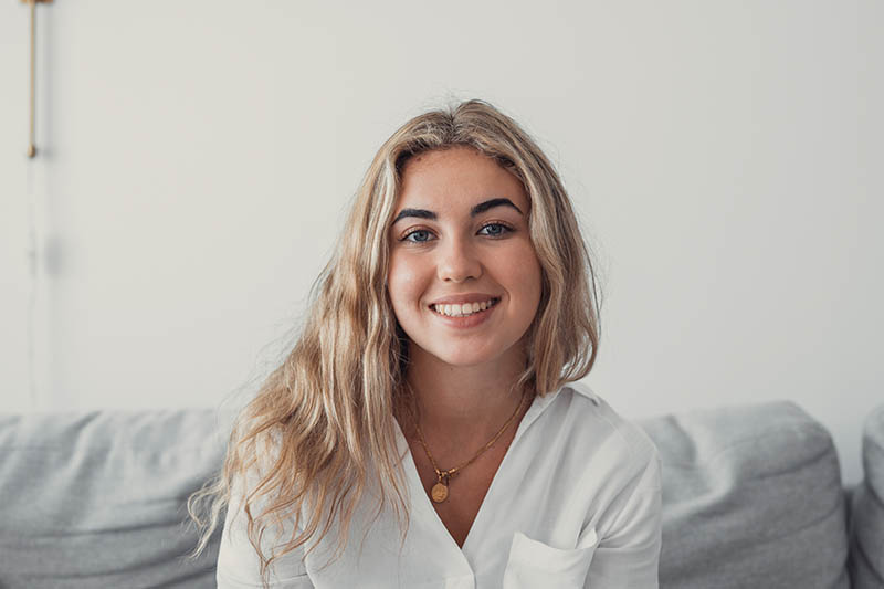 Screen view of happy millennial Hispanic woman look at camera ha Happy young woman with blonde hair smiling at the camera in a well lit room.